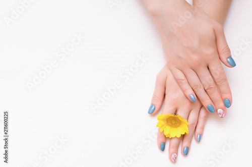 Woman hands with manicure on nails and yellow flower.