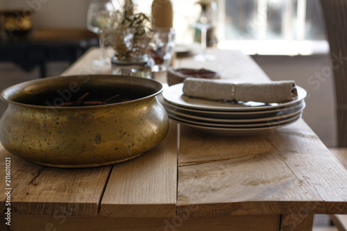 Closeup shot of a wooden table with porcelain plates and copper dish