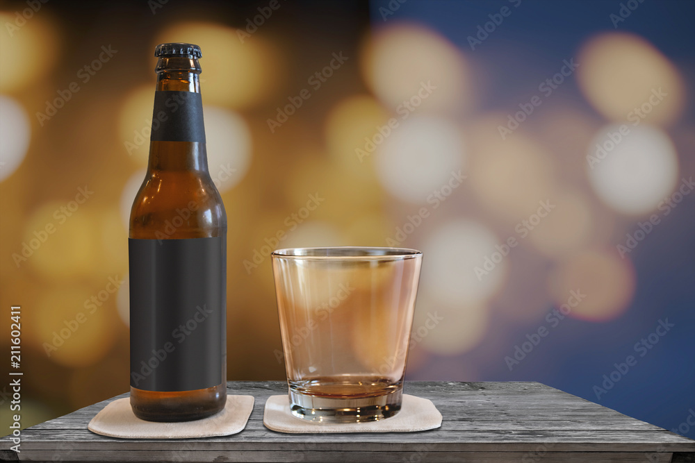 Small beer bottle with a glas on a table with a blur bokeh Small beer bottle with a glas on a table with a blur bokeh