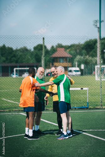 interracial elderly football players after match on green field