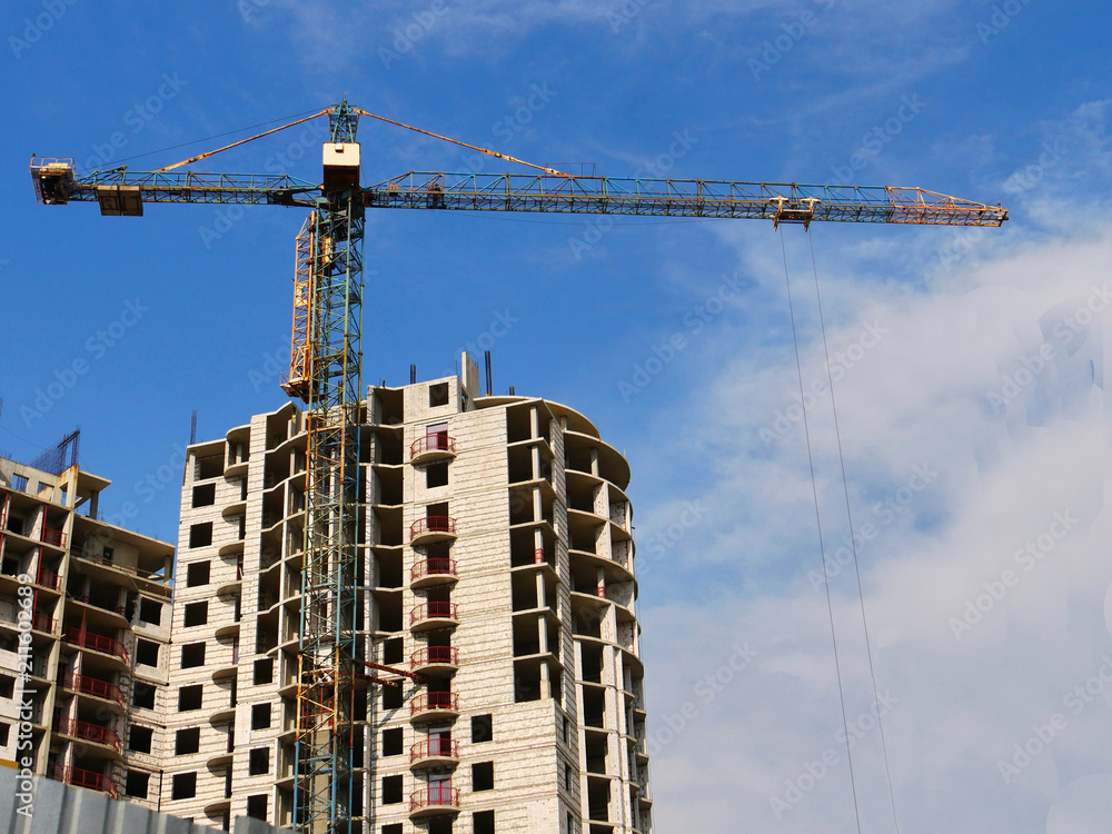 Building and crane under construction against blue sky.