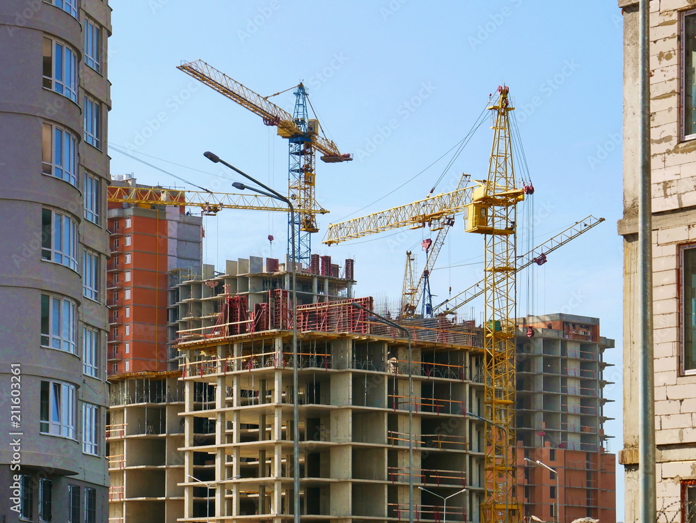 Construction site. Industrial cranes near buildings under construction.