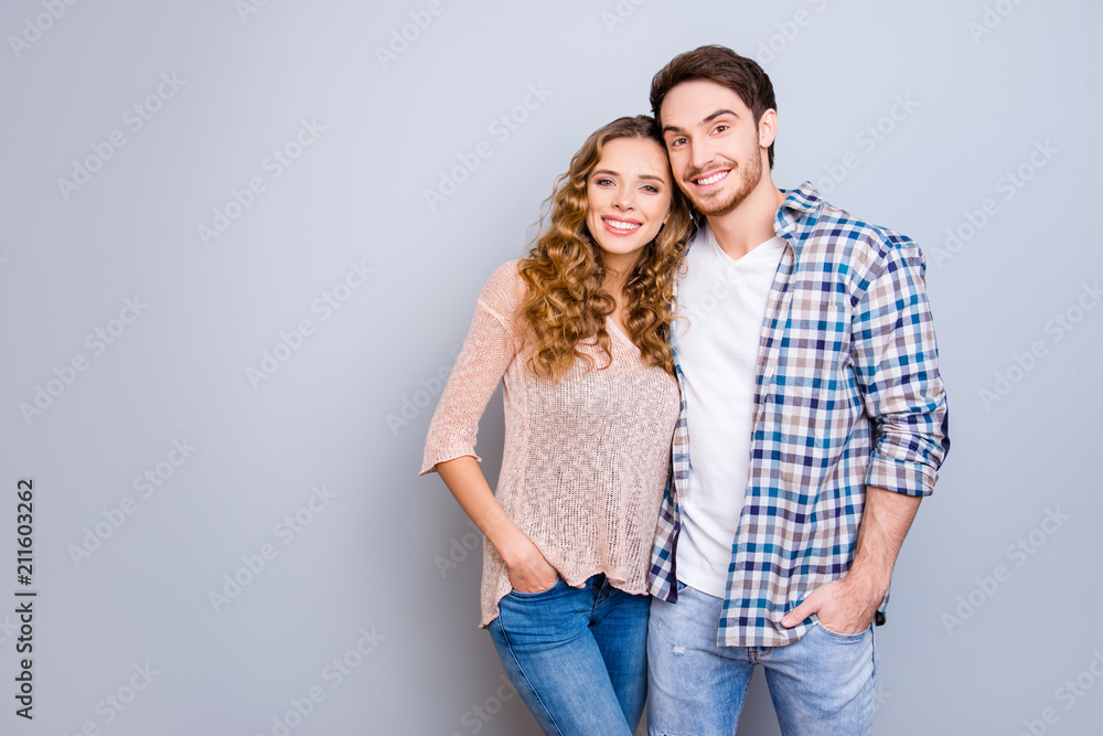 Portrait with copysapce empty place of attractive successful couple in casual outfits holding hands in pocket of pants hugging looking at camera isolated on grey background Portrait with copysapce empty place of attractive successful couple in casual outfits holding hands in pocket of pants hugging looking at camera isolated on grey background