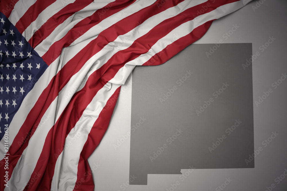 Naklejka premium waving national flag of united states of america on a gray new mexico state map background.