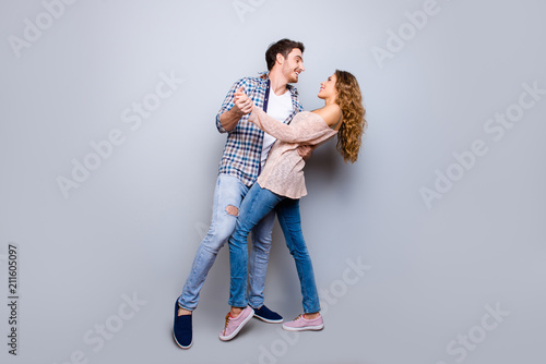 Full body portrait of creative cheerful couple in casual outfits dancing enjoying activity isolated on grey background. Move motion life art concept