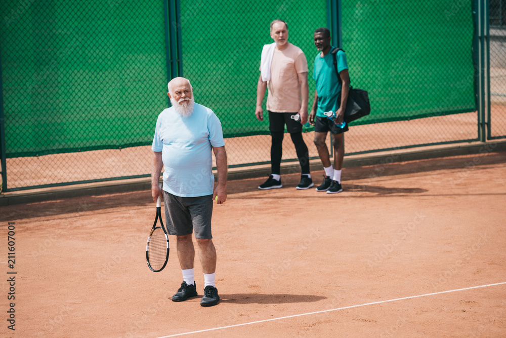 multiracial elderly men standing on tennis court