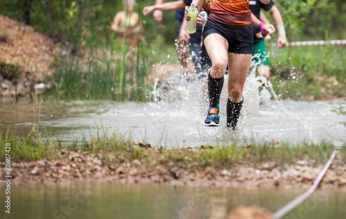 Trail runners moving through water and mud on rural road