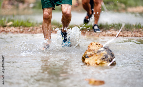 Trail runners moving through water and mud on rural road