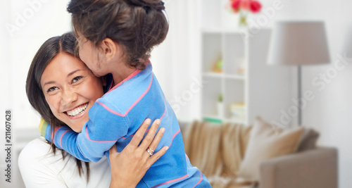 family, motherhood and people concept - happy mother and daughter hugging and kissing over home room background