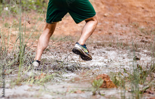 Running through dirty puddle splashing mud, cross country trail