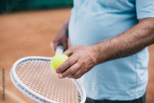 partial view of old man with tennis equipment in hands © LIGHTFIELD STUDIOS