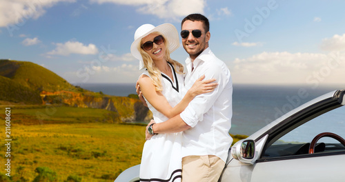 travel, love, date and people concept - happy couple hugging near convertible car over big sur coast of california background