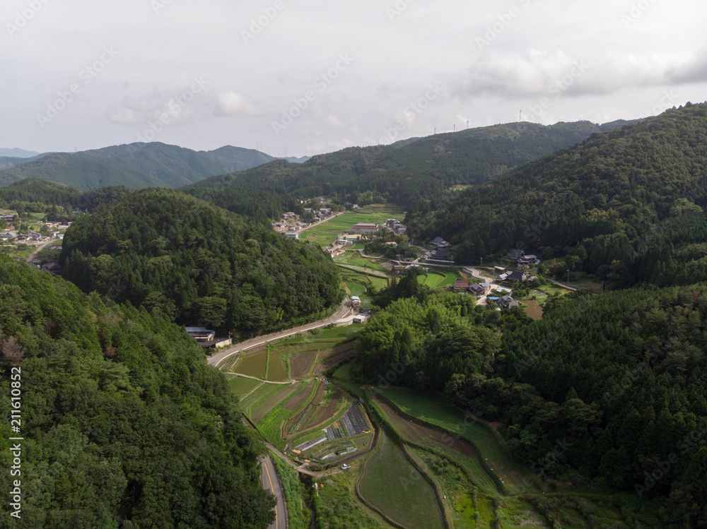 Rice fields in valley surrounded by forested mountains in rural Japan Rice fields in valley surrounded by forested mountains in rural Japan