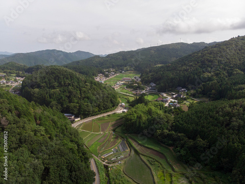 Rice fields in valley surrounded by forested mountains in rural Japan