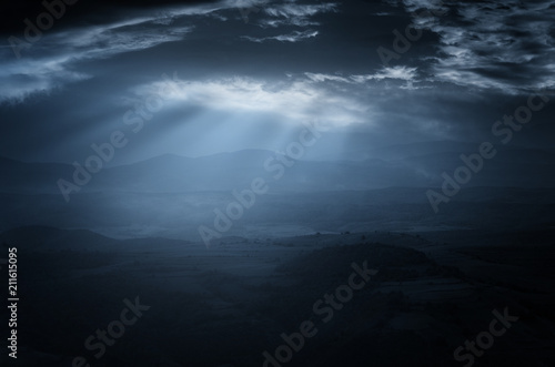 dark sky with moonlight piercing through storm clouds  dark landscape background