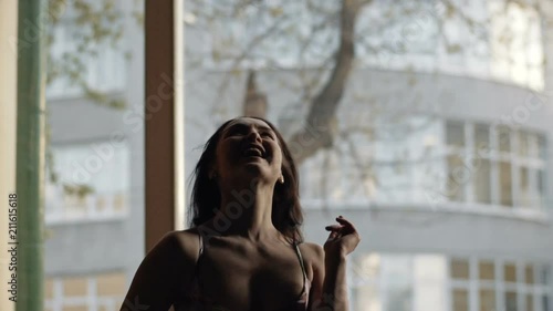 Slow motion portrait of graceful girl dancing against the window, jumps and expresses great joy