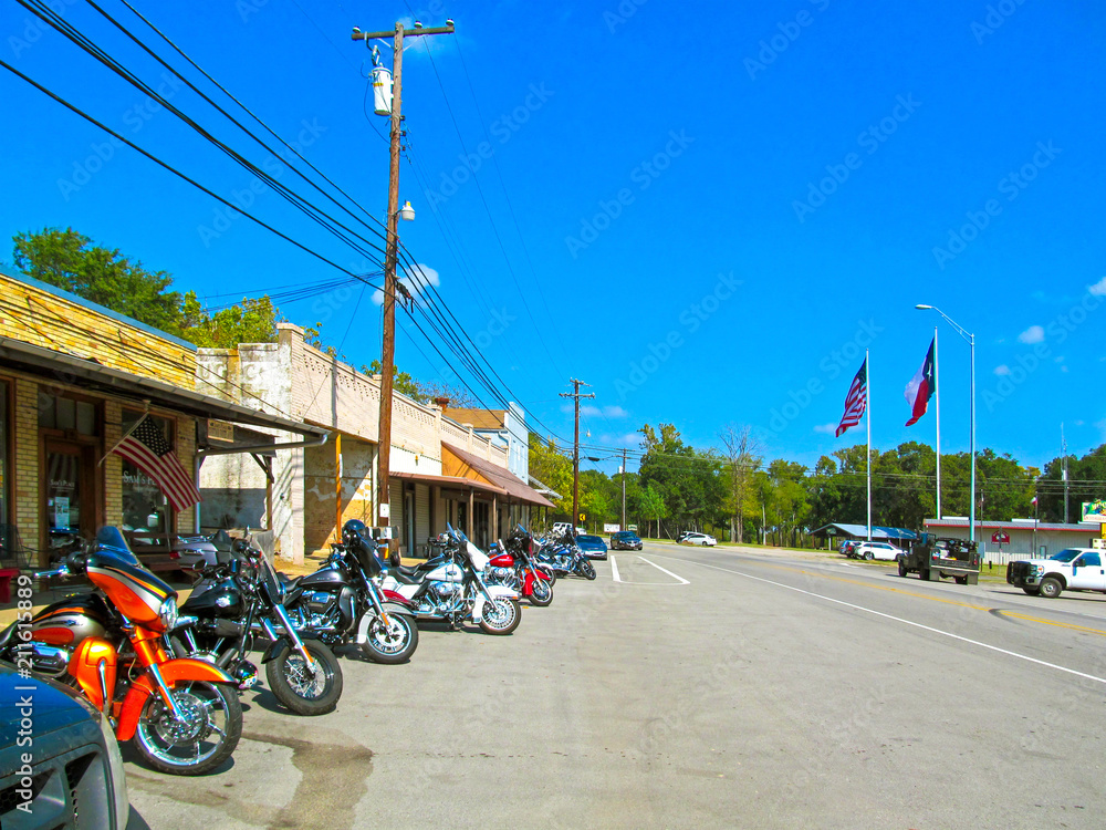 Naklejka premium Parking motorcycles in a row along the street. Motorbikes of bikers parked at the usual meeting place near Canton in Texas on a sunny day during a weekend trip. 