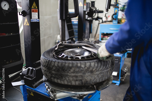 Fototapete Mechanic repairing tire. Worker vulcanize used tire.