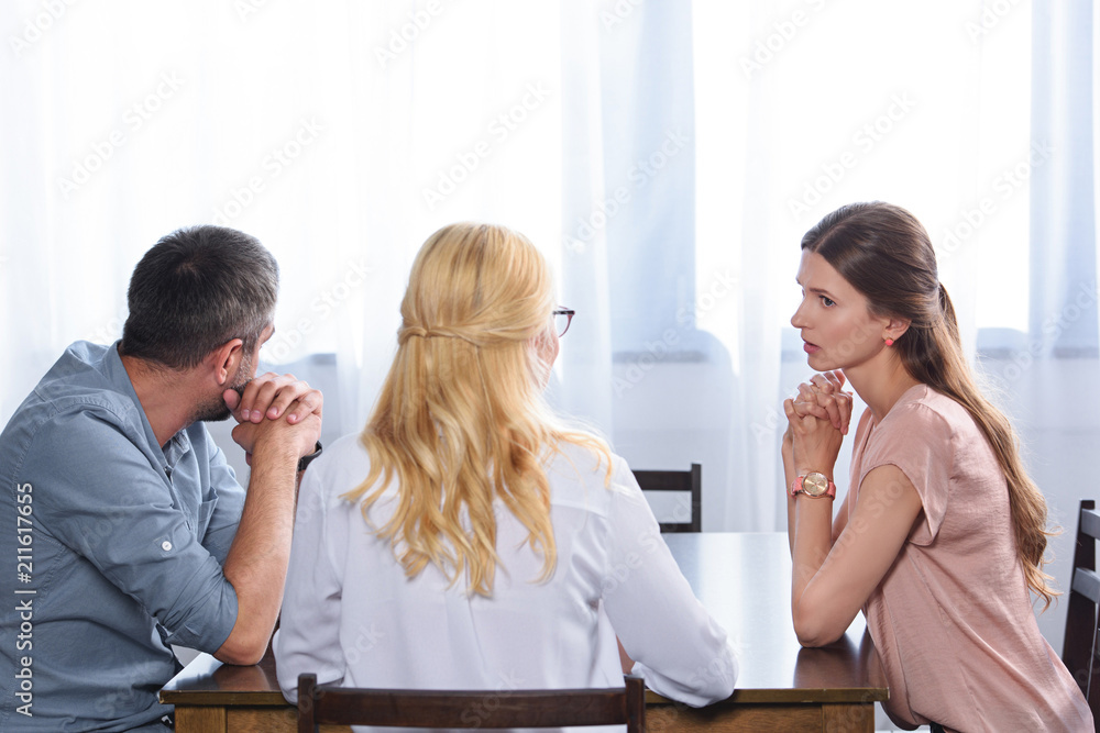 rear view of female psychiatrist talking to couple on therapy session in office rear view of female psychiatrist talking to couple on therapy session in office