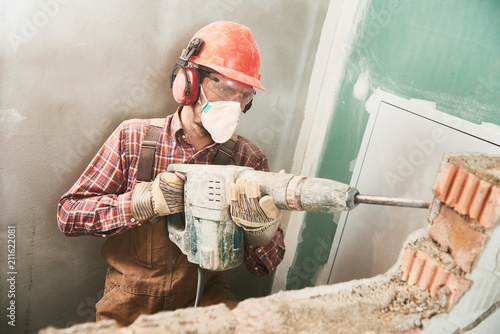 worker with demolition hammer breaking interior wall
