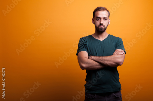 Serious handsmone man posing in studio on yellow background