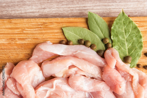 Pieces of fresh chicken fillet, bay leaf and black pepper closeup photo