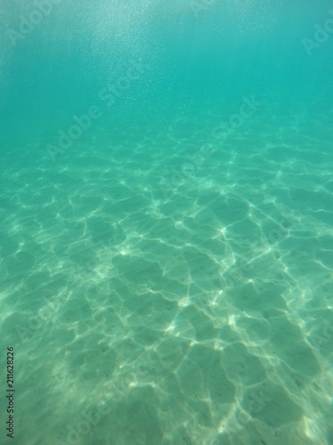 Fondo de la playa bajo agua cristalina