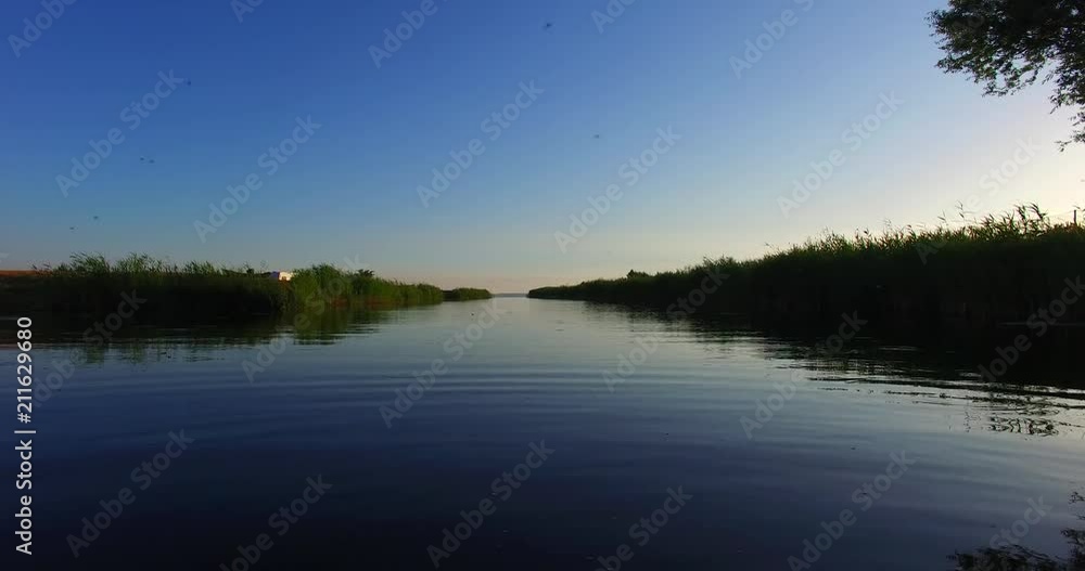 The quiet channel in the evening. From the water jumping fish, swarm of mosquitoes, the rushes, reflections in the water and clear, blue sky.