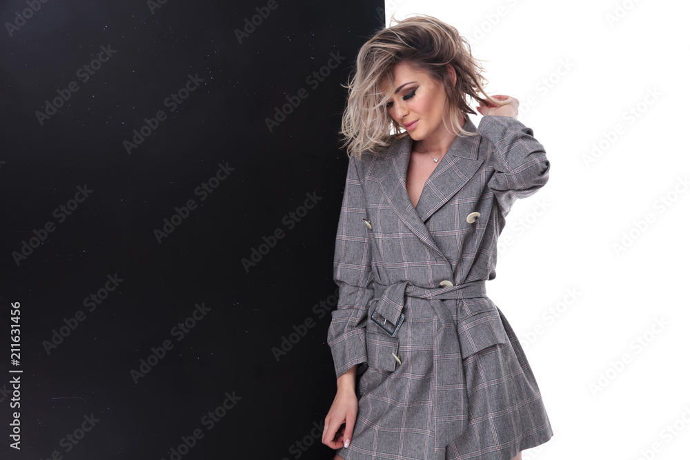 beautiful woman wearing grey suit looks down while holding hair beautiful woman wearing grey suit looks down while holding hair