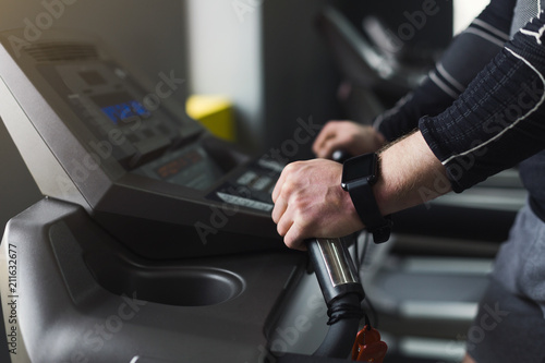 Unrecognizable man in gym running on treadmill