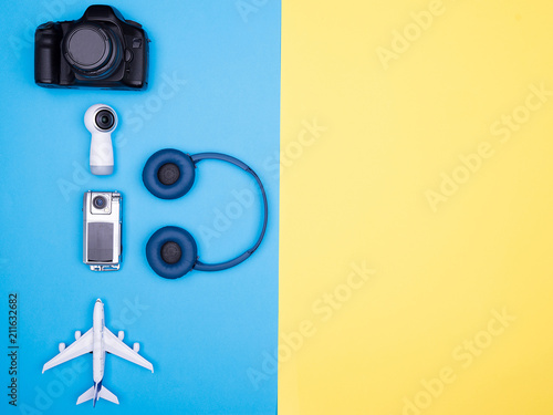 Flat lay top view of plane on yellow background, next to camera and headphones