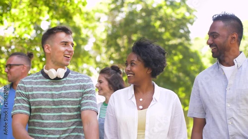 people, friendship and international concept - group of happy friends walking in park