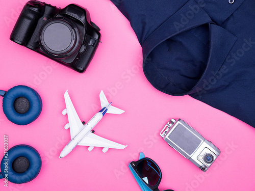 flat lay top view of traveler photographer accessories on pink background. camera , sunglasses. headphones. shirt