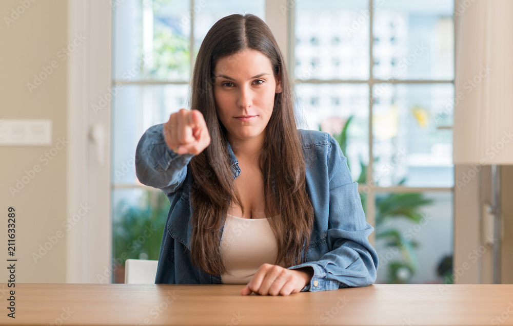 Young beautiful woman at home pointing with finger to the camera and to you, hand sign, positive and confident gesture from the front Young beautiful woman at home pointing with finger to the camera and to you, hand sign, positive and confident gesture from the front