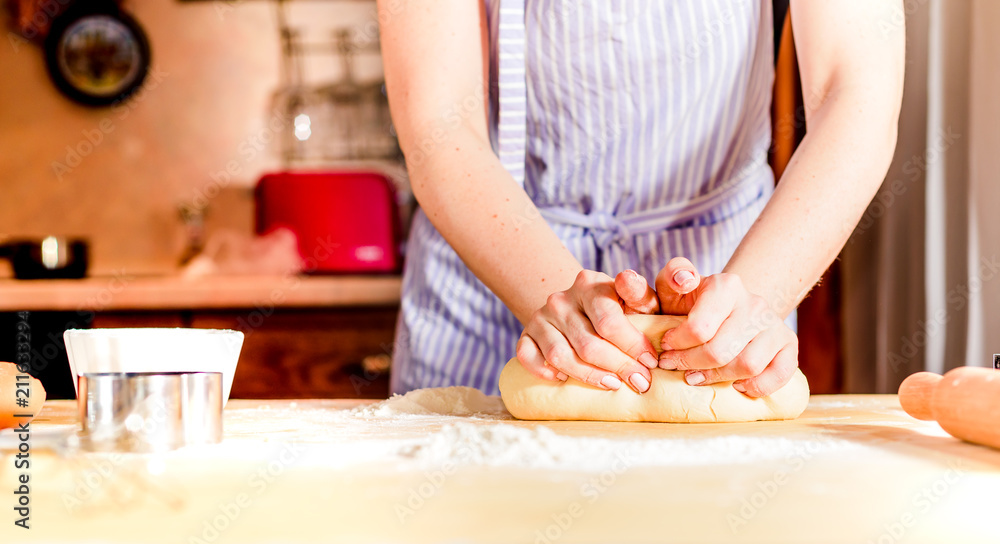 Female hands making dough on wooden table
