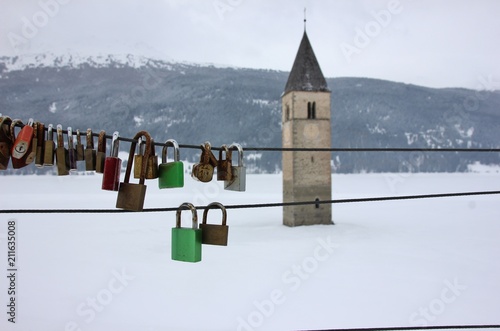 Lucchetti appesi di fronte al Campanile sommerso nel Lago di Resia, Alto Adige, Italia photo