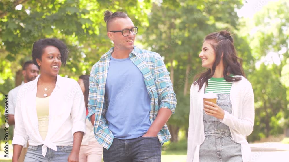 people, friendship and international concept - group of happy friends with coffee walking and talking in park people, friendship and international concept - group of happy friends with coffee walking and talking in park