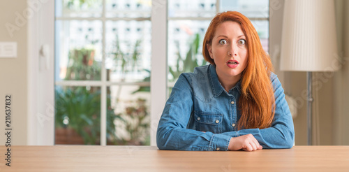 Redhead woman at home afraid and shocked with surprise expression, fear and excited face. Free Download Redhead woman at home afraid and shocked with surprise expression, fear and excited face. - GFXLoad