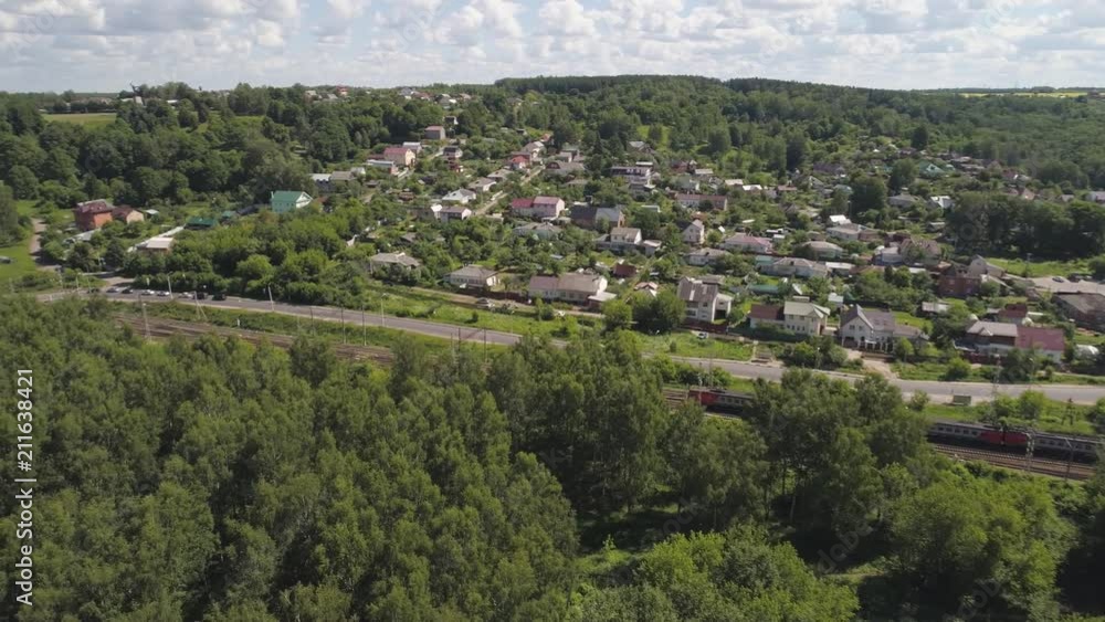 Highway with motor vehicles and a railway with an electric train in the countryside. Aerial view transport infrastructure with highway and railway. Highway with motor vehicles and a railway with an electric train in the countryside. Aerial view transport infrastructure with highway and railway.