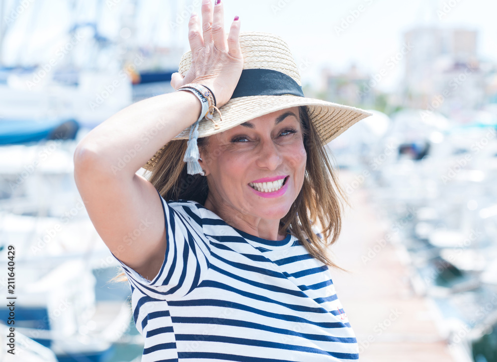 Beautiful middle age woman standing in marina stressed with hand on head, shocked with shame and surprise face, angry and frustrated. Fear and upset for mistake.