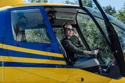 My hobby. Beautiful female pilot sitting in a helicopter and posing for the camera while smiling elatedly photo