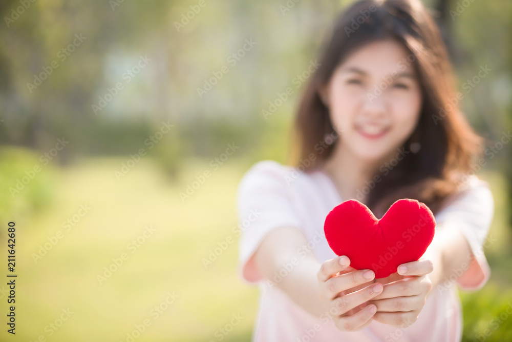 Selective focus Woman hold red  heart in the park .  Concept of the Valentine's Day.