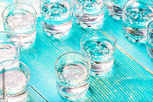 chaotically arranged glass glasses from under a liquor on a blue table