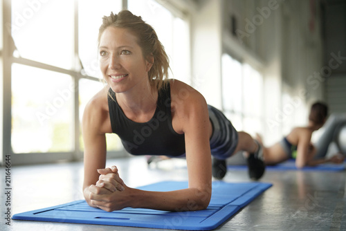 Beautiful blond woman at the gym doing pushups exercises