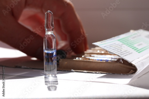 Novocaine in ampoule on the table and a doctor hand on the background.
 photo