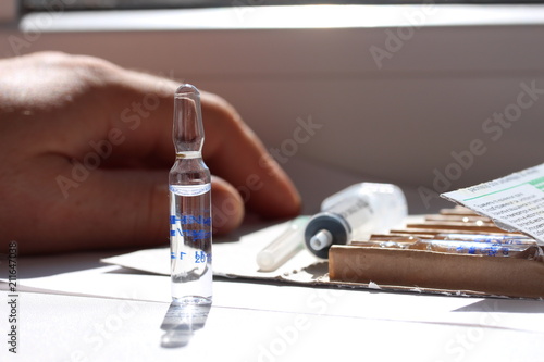 Novocaine in ampoule on the table and a doctor hand on the background.
 photo