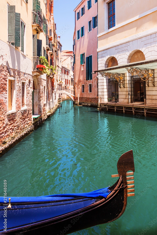 Traditional blue Venetian vintage boat gondola with retro ferry prow-head on Italy historical buildings and canal blue sky background summer sunny day