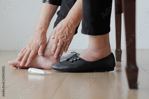  Elderly woman putting cream on swollen feet before put on shoes © toa555