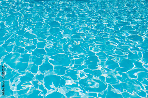 Blue and bright water surface and ripple wave with sun reflection in swimming pool