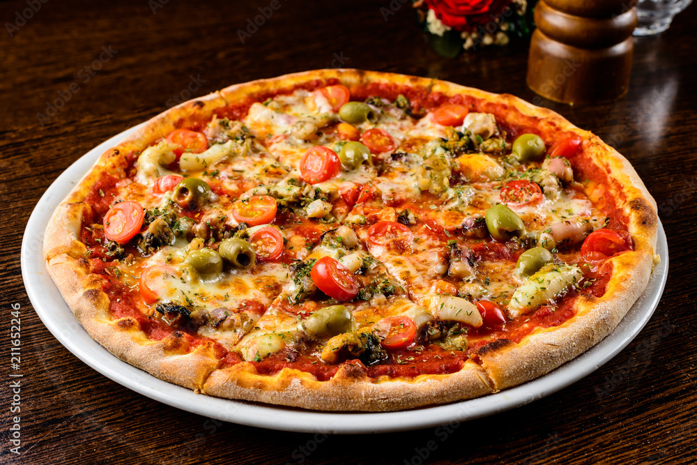 Tasty warm pizza with bacon, tomatoes, cheese and olives on the 